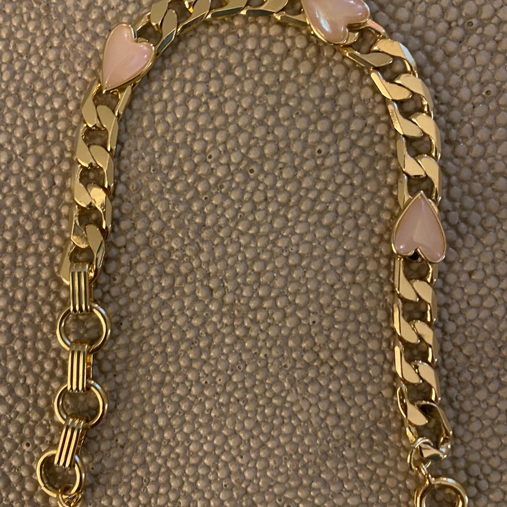 Gold bracelet with pink hearts.